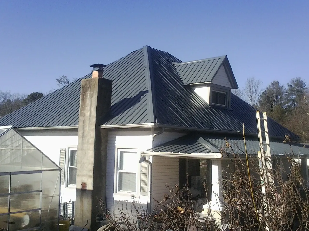 Dark blue standing seam metal roof on a white farmhouse with dormer — Slate & Tile Roof Repair by Roofing Brothers in Brightwaters