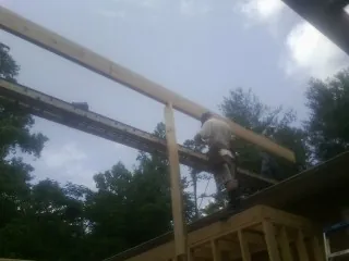 Carpenter setting a ridge beam over a new addition frame — Ice Dam Removal by Roofing Brothers in Brightwaters