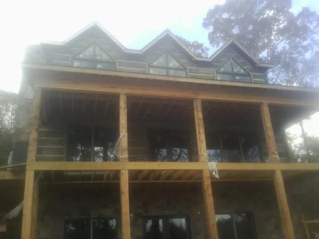 Dormers and porch framing on a large log home under construction — Roof Coating work by our crew in Brightwaters