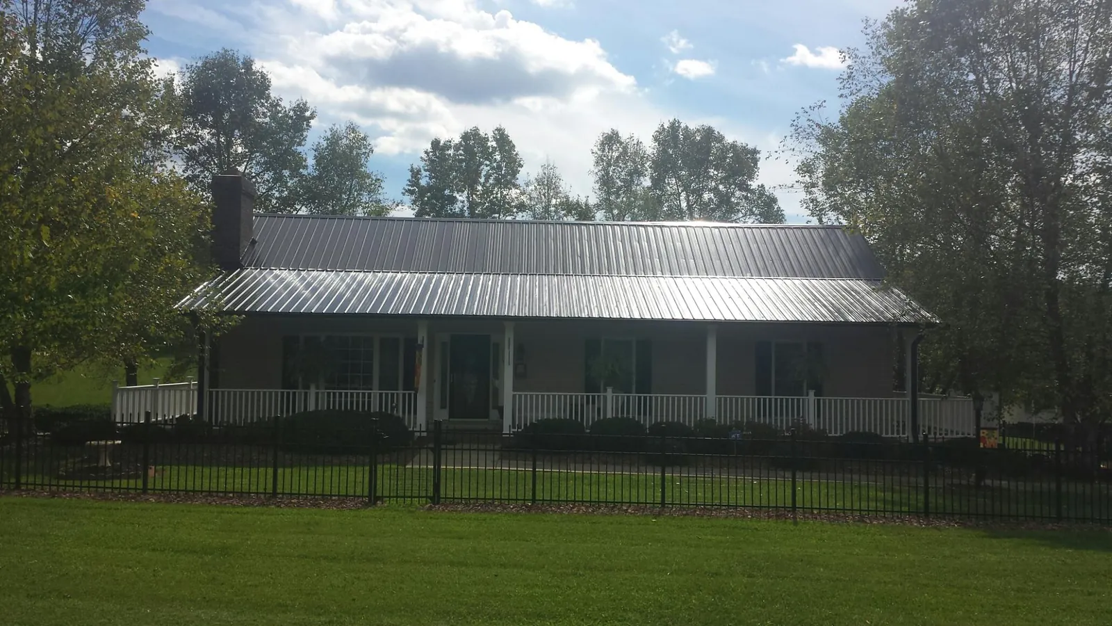 Gray metal roof on a brick ranch with a full width front porch — Gutter Guard Installation work by our crew in Brightwaters