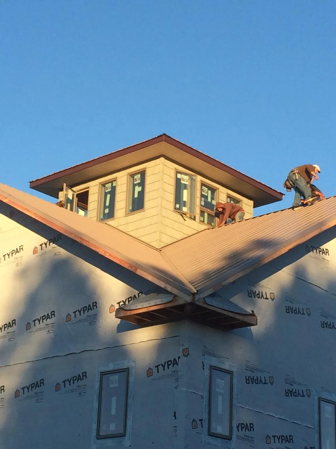 Roofers working around a rooftop cupola on a new metal roof at sunset — Roof Waterproofing in Brightwaters by Roofing Brothers